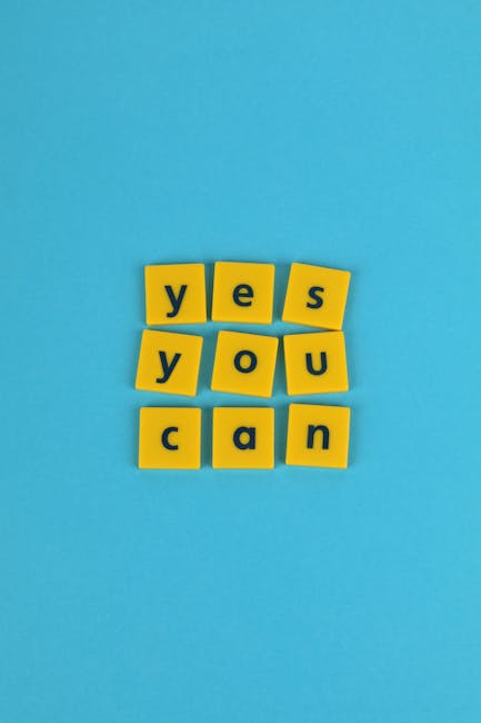 An arrangement of eight yellow Scrabble tiles on a bright blue background spells out the phrase 'yes you can,' with each tile featuring bold black letters. The tiles are neatly aligned in four rows, c